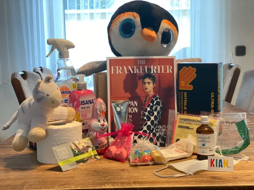 Der Inhalt eines COVID-Kits auf einem Tisch: Kuscheltiere, Desinfektionsmittel, Seife, Einweghandschuhe, Masken und Süßigkeiten.