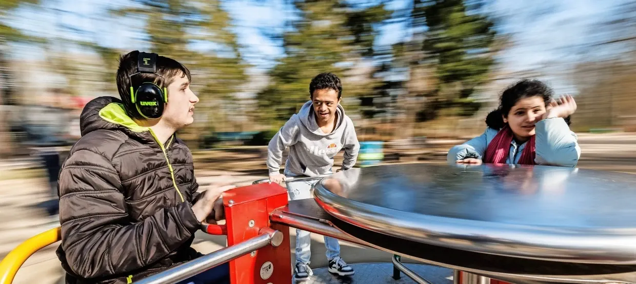 Drei Jugendliche fahren auf dem Rolli-Karussell am Goetheturm, der Hintergrund verwischt in der Drehung. Einer von ihnen trägt einen Gehörschutz.