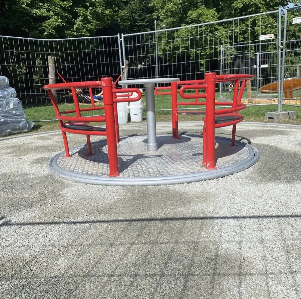 Das neu montierte rote Karussell im Grüneburgpark, noch von einem Bauzaun umgeben.
